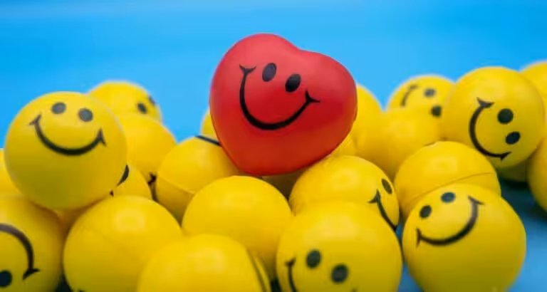 Glückliche gelbe Bälle mit Smileys und rotes Herz, kreative Gestaltung.