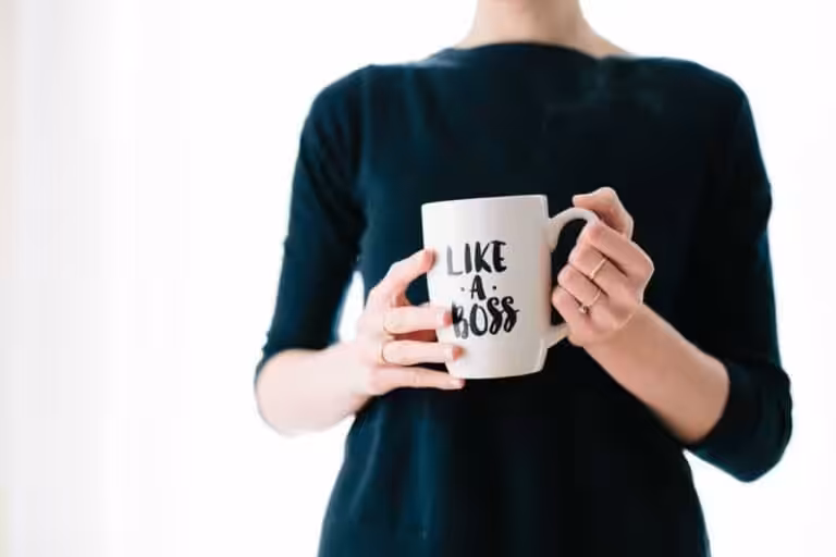 Frau hält Tasse mit "Like a Boss" Schriftzug, Fokus auf Hände.